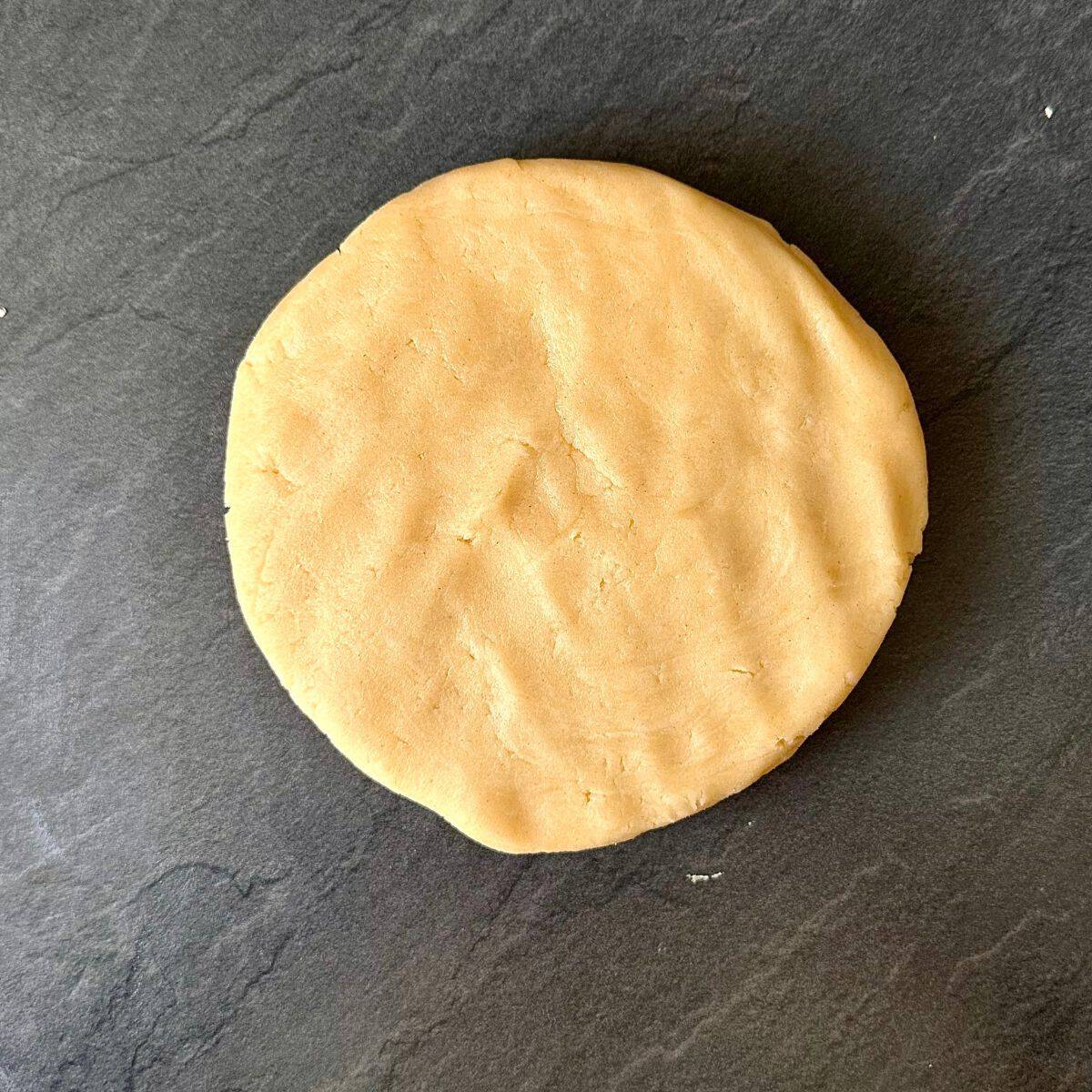 A round slab of shortcrust pastry dough on a grey worktop background. For a beetroot and goats cheese tart.