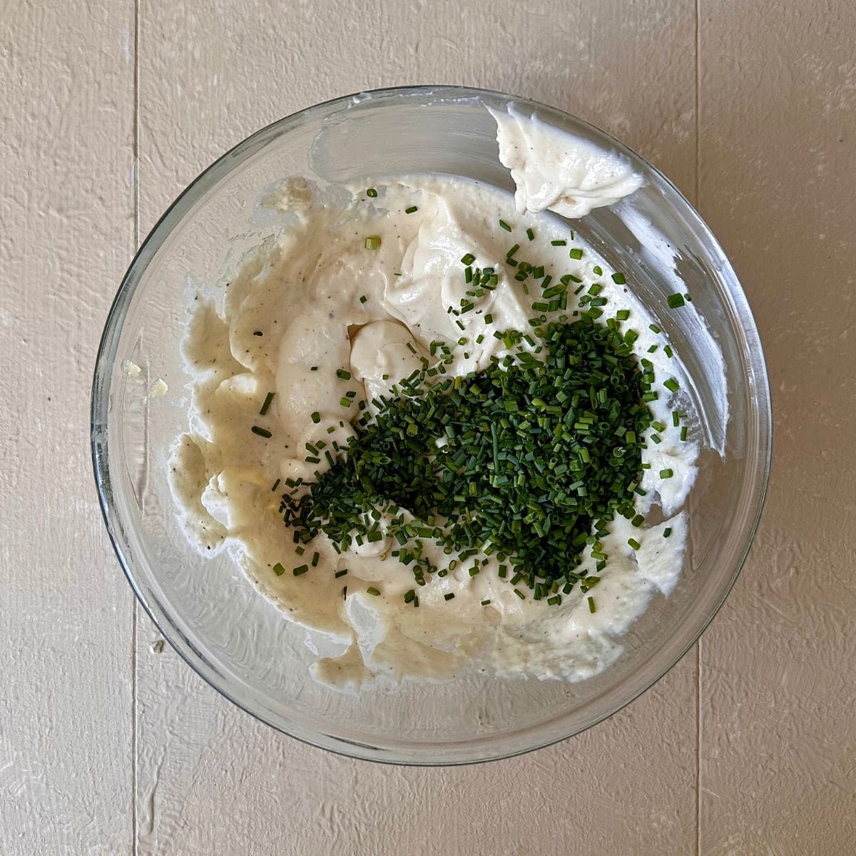 A glass bowl containing goats cheese mixed with cream cheese and finely chopped chives are on top, ready to mix in. For a beetroot and goats cheese tart.