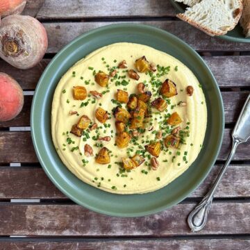 Golden beetroot dip on a green plate garnished with roasted golden beetroot and chives.