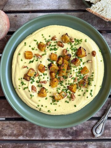 Golden beetroot dip on a green plate garnished with roasted golden beetroot and chives.