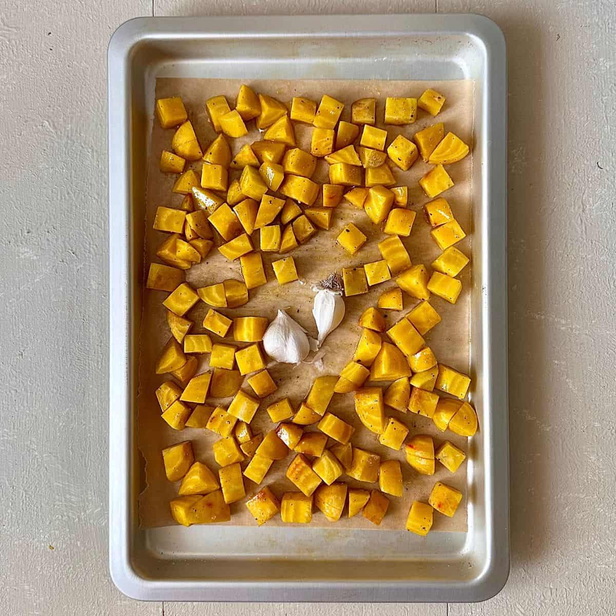 Golden beetroot cut into small dice, marinated in olive oil, salt and pepper, spread out onto a baking tray ready for roasting. For a beetroot dip recipe.