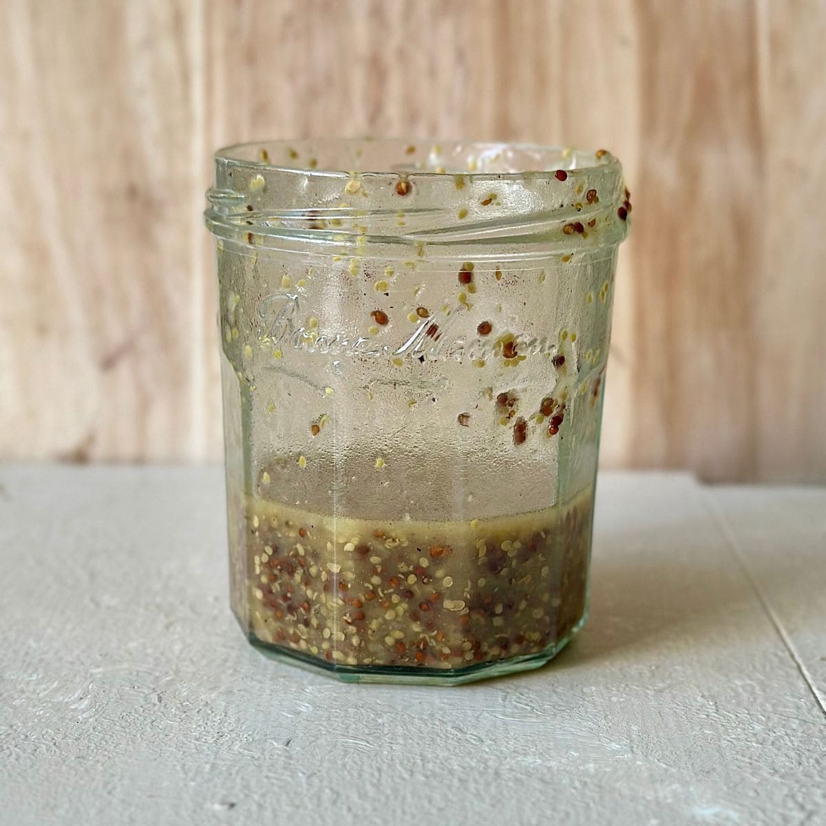 A jam jar containing a wholegrain mustard salad dressing for a borlotti bean salad.