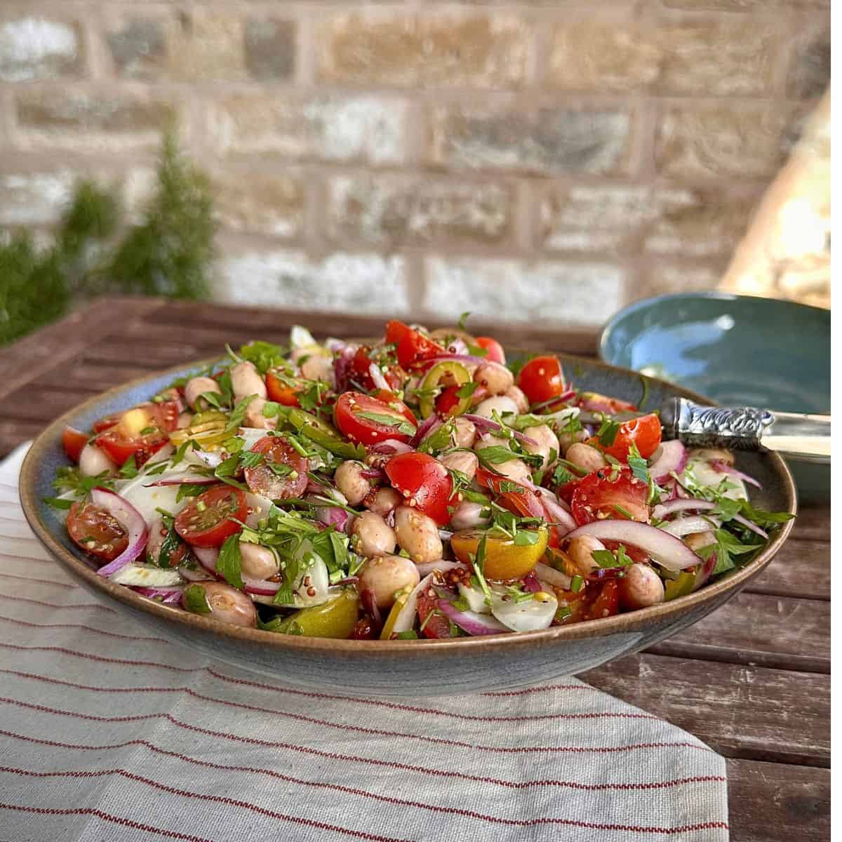 A plate of borlotti bean salad on a slatted wooden table.