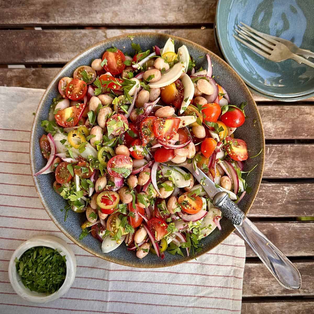 A plate of borlotti bean salad with a spoon resting on the salad.