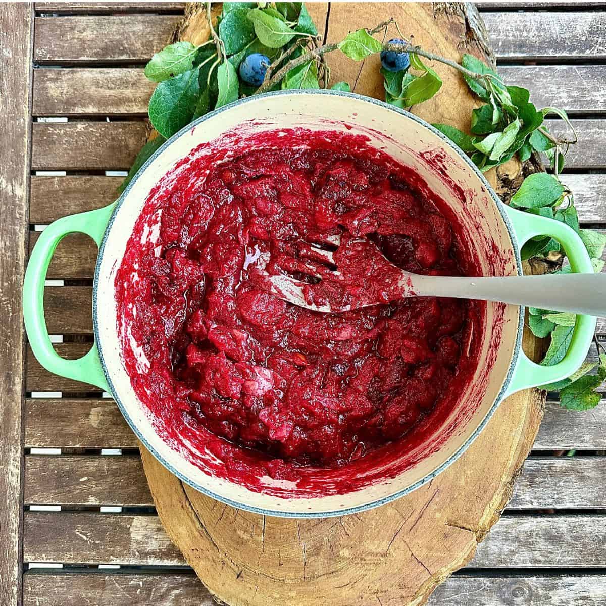 A large green pot containing crab apples and damsons after cooking in water. Showing a deep red, mushy mix. For a fruit leather recipe.