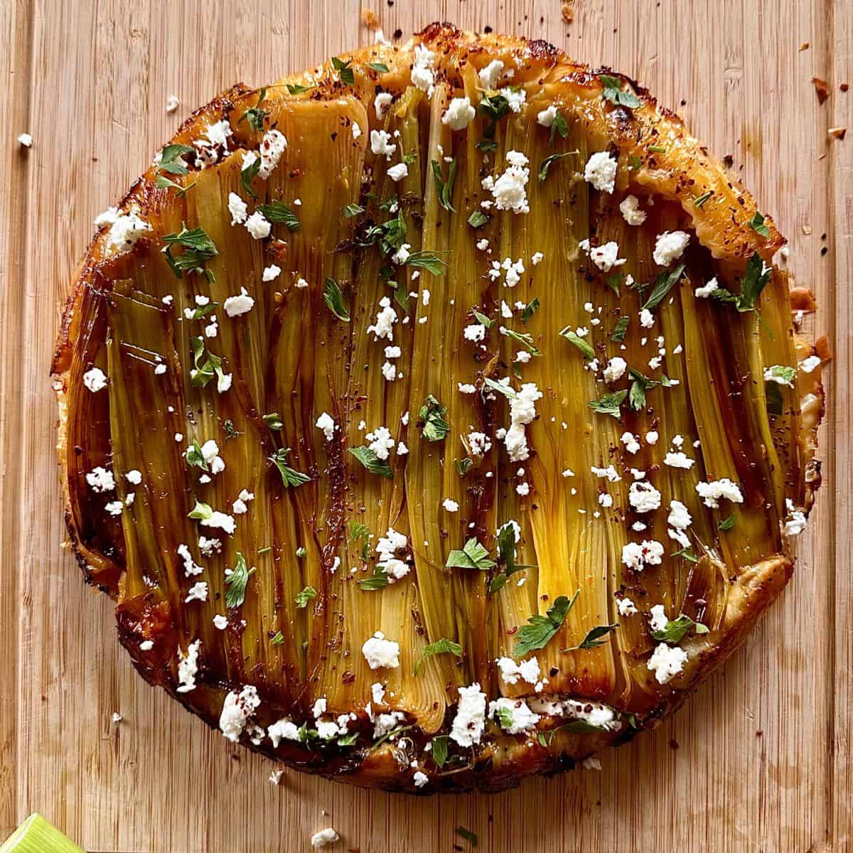 A leek tarte tatin with crumbles feta, Aleppo pepper and chopped parsley sprinkled over the top.