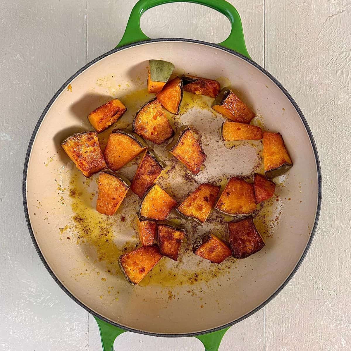 A large green pan containing diced crown prince pumpkin, pan fried to a golden brown colour. For a pumpkin orzo recipe.