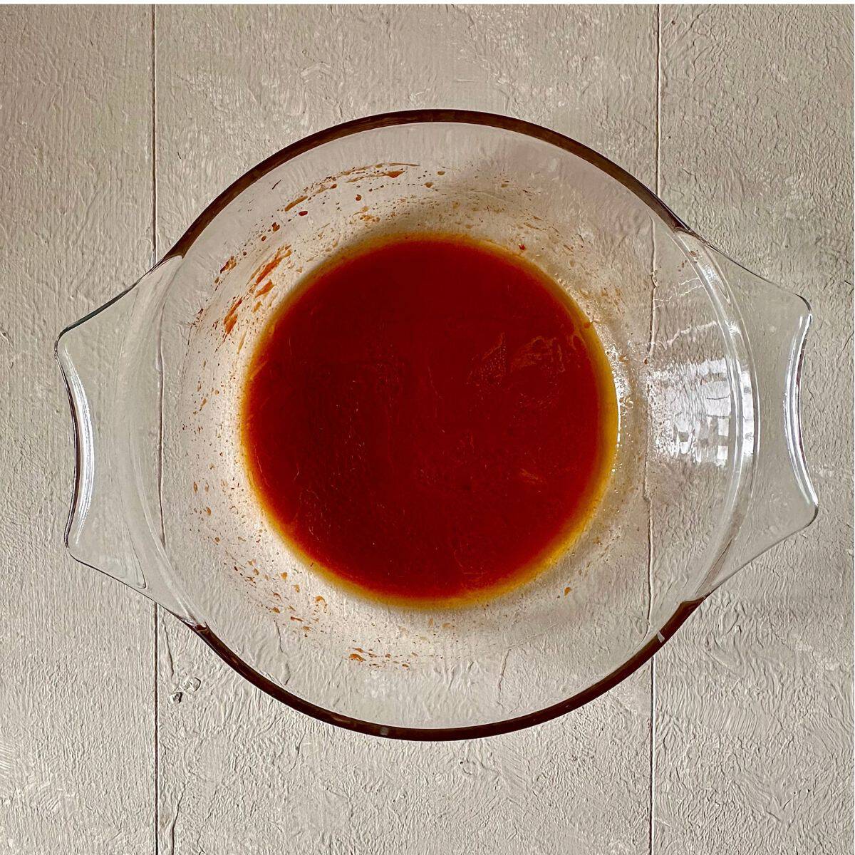 A glass bowel containing gochujang paste, olive oil, lemon juice and salt, mixed together for a marinade for beetroot skewers.