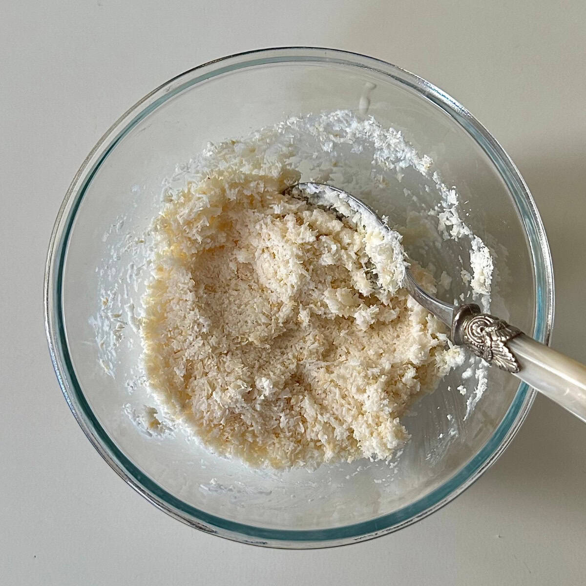 A glass bowl contains desiccated coconut mixed with coconut milk. For a golden beetroot thoran recipe.