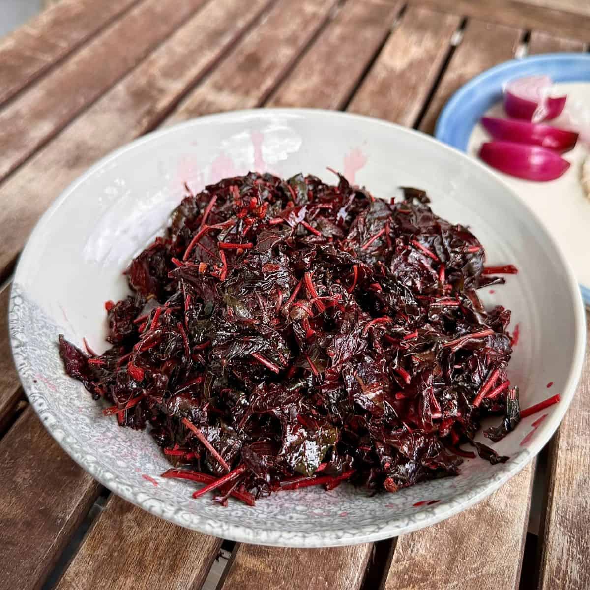 A dish containing cooked amaranth with Panch phoran, garlic, Kala Namak and mustard oil. For a lal saag recipe.
