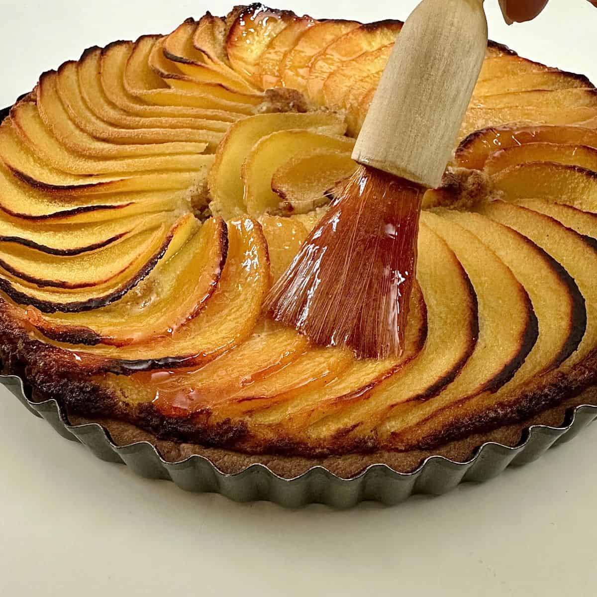 A glaze being brushed onto a quince frangipane tart.