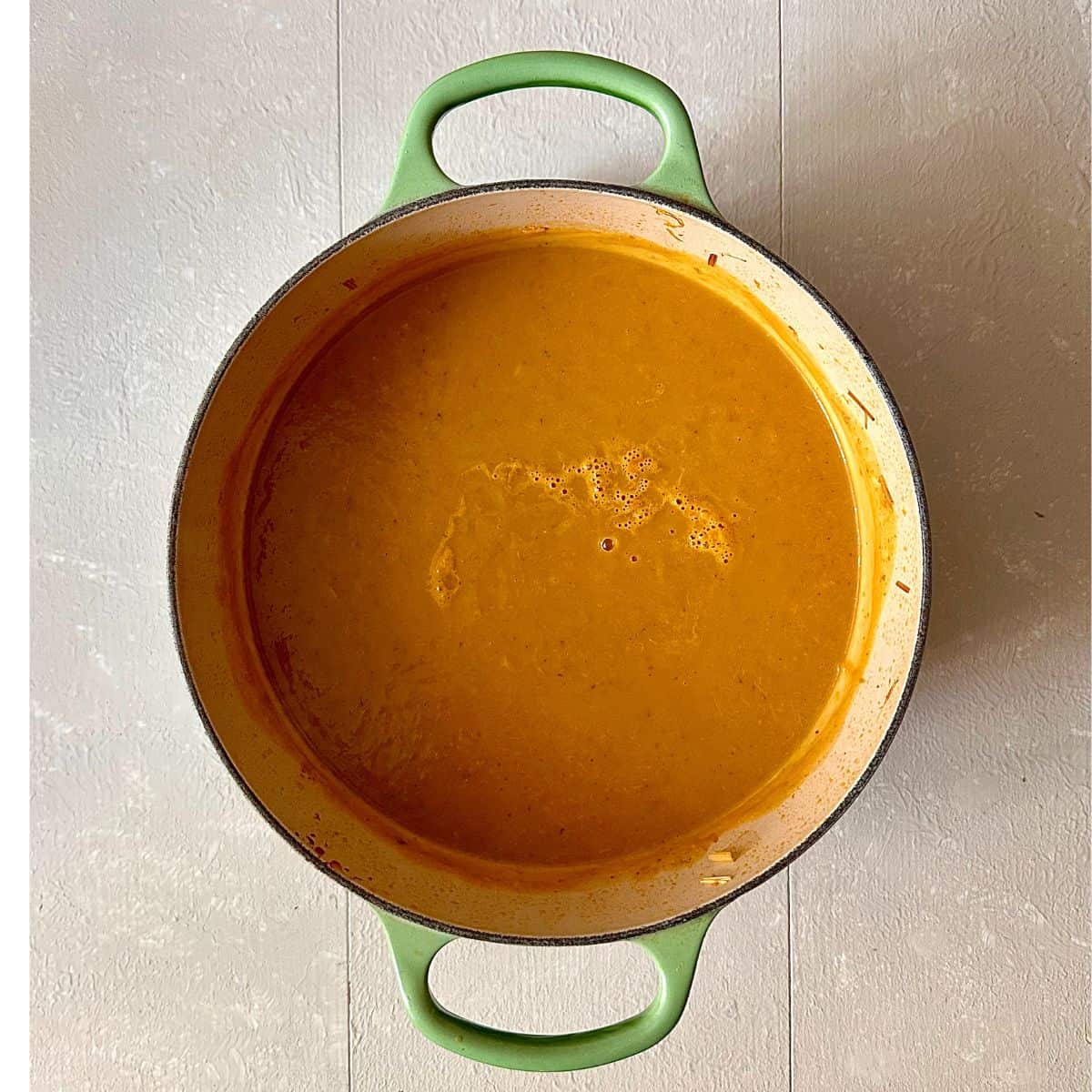 A large green pot containing blended thai pumpkin soup.