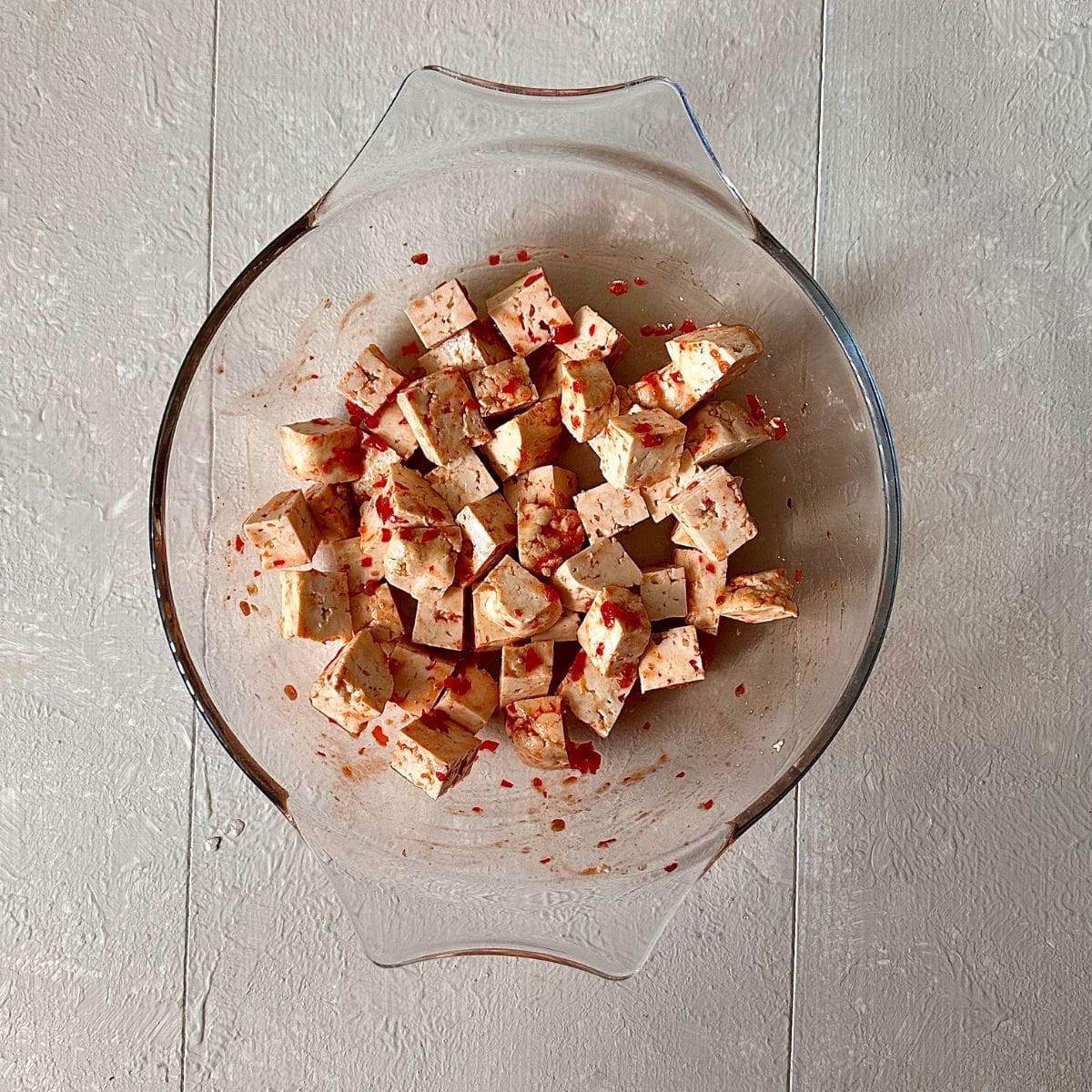 Diced smoked tofu coated in sambal paste in a glass dish. For a thai pumpkin soup recipe.