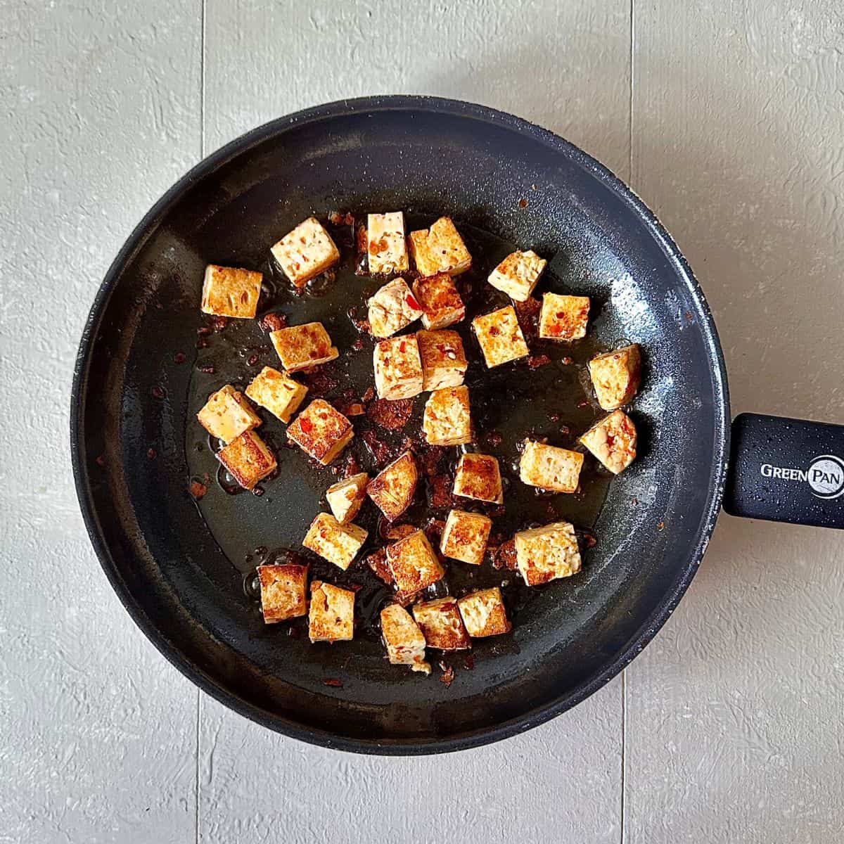 A frying pan containing fried smoked tofu cubes for a thai pumpkin soup recipe.