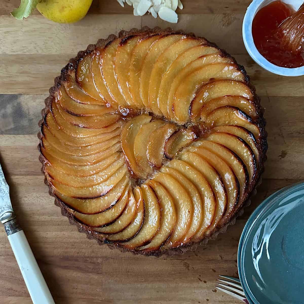 A vegan quince frangipane tart on a wooden chopping board background.